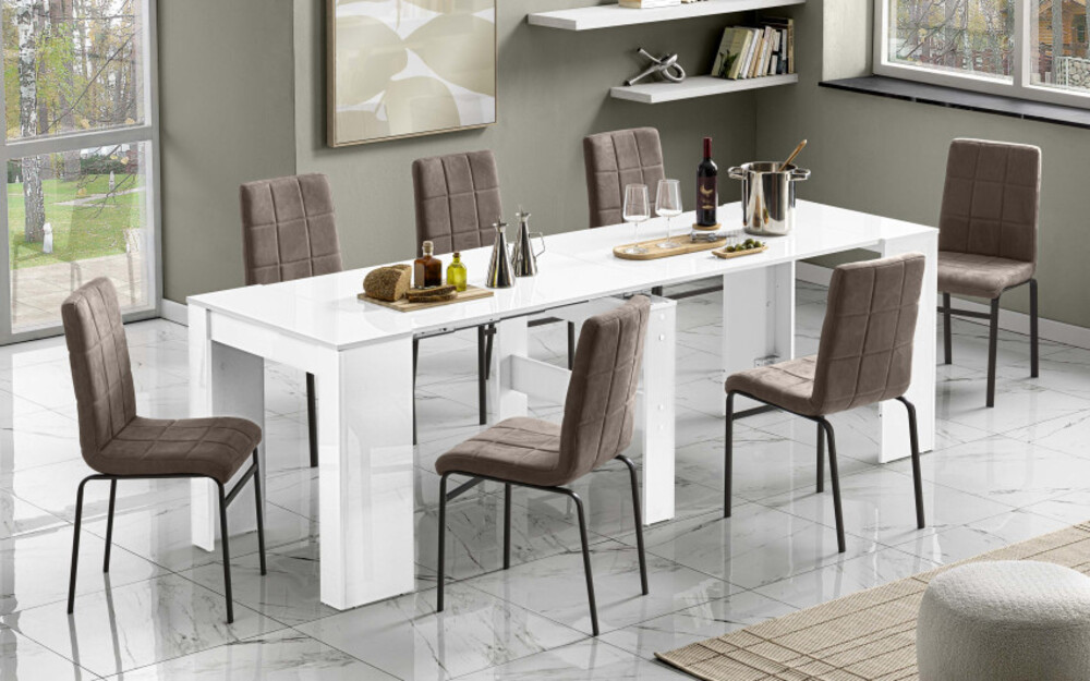 Lungo tavolo da pranzo bianco lucido allungabile circondato da sedie moderne bianche